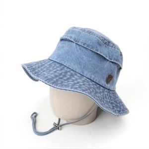 Blue denim bucket hat with wide brim, adjustable chin strap, and metal logo emblem