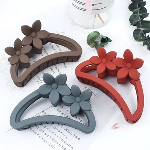 Matte floral hair claw clips in coffee, red, and blue grey colors shown from a top view