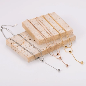 Double-layered necklace set featuring ball pendants in gold, silver, and rose gold finish