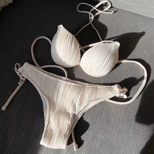 Flat lay of cream bikini set with vertical ribbed texture and side tie details
