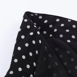 Vista dettagliata del tessuto chiffon nero a pois bianchi e cuciture di precisione