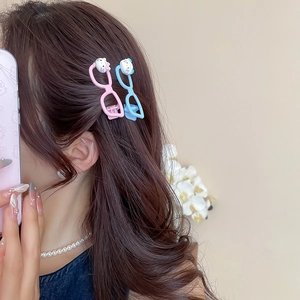 Detail shot of cute cat cartoon glasses hairpins in pink and blue worn by a model