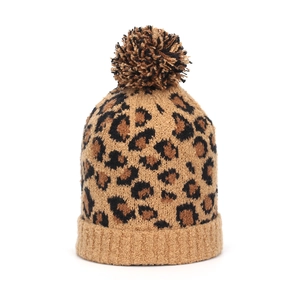 Close-up of leopard print knit beanie with a fluffy faux fur pom and ribbed cuff
