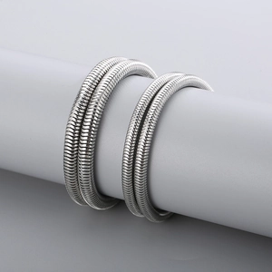 Detailed view of silver snake bone chain bracelets with smooth metallic texture on a stand