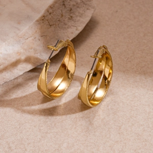 Fashionable gold-tone layered hollow hoop earrings on natural stone background