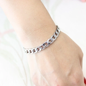 Close-up of a silver Cuban link bracelet worn on wrist showing premium stainless steel finish