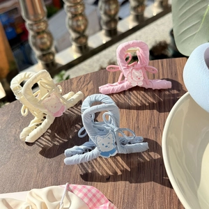Lace plaid bow hair clips in cream, pink, and blue colors on a rustic wooden table
