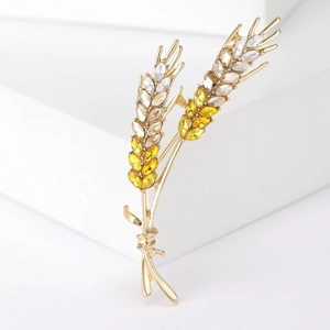 Detail of wheat ear brooch with gold metal and yellow faceted crystals on white background