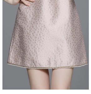 Macro detail of luxury jacquard fabric with elegant white pearl trim on dress hemline