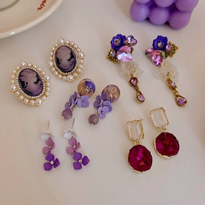 Macro view of vintage purple crystal earrings with faux pearls and rose floral details