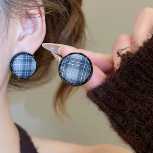 Close-up of blue-grey plaid fabric round stud earrings with minimalist black frames