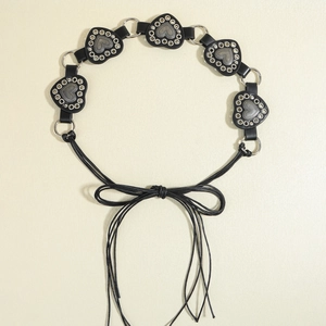 Close-up of black leather belt with heart-shaped riveted plates and knotted tie closure