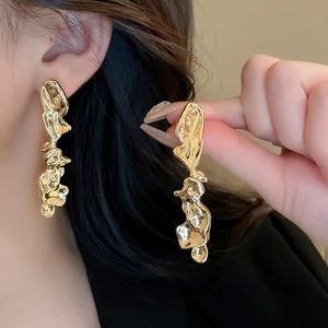 French irregular molten metal earrings in gold finish worn by a model in a close-up shot