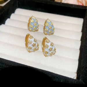 Detailed macro view of retro enamel flower hoop earrings with zircon stones in a jewelry box