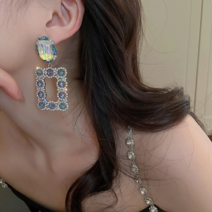 Close-up of luxury rectangular leaf earrings with emerald blue stones and rhinestones