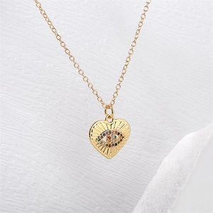 Macro d'un collier pendentif cœur doré avec détail d'œil en zircons colorés