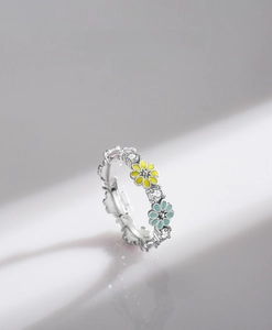 Detail of 925 silver ring featuring blue and yellow enamel daisies with zircons