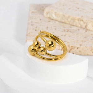 Dettaglio di un anello a più strati dorato con sfere lucide su un piedistallo