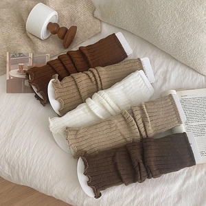 Detailed knit leg warmers with ruffle edges in beige and coffee colors on a soft background