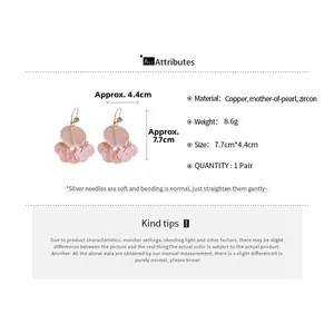 Detail view of mother-of-pearl tassel earrings with zircon and copper materials