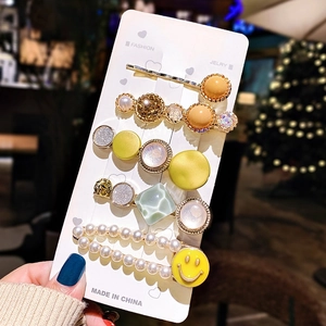 Detail of five-piece hair clip set with faux pearls, glitter, and a yellow smiley face