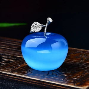 Close-up of blue crystal apple ornament with diamond-encrusted leaf on a wooden base