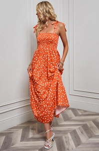 Detailed close-up of the ruffled bodice and adjustable tie straps on the orange polka dot dress