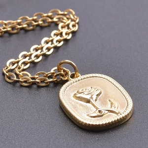 Macro view of golden rectangle necklace pendant with embossed rose and beaded edge detail