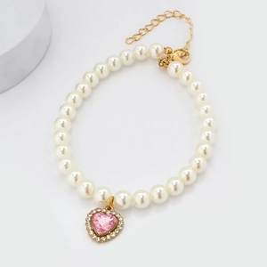Detail of pet pearl necklace with pink heart crystal pendant and golden clasp