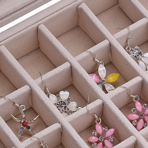 Macro detail of beige flocked jewelry organizer box with multi-compartment dividers