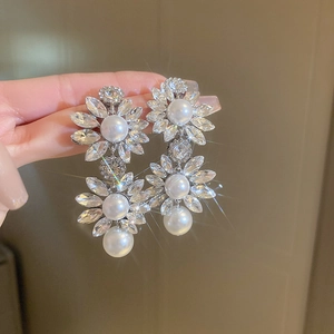 Close-up of double flower drop earrings with rhinestones and white pearls on silver studs
