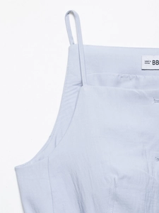 Detail of light blue camisole neckline and thin shoulder straps on woven fabric