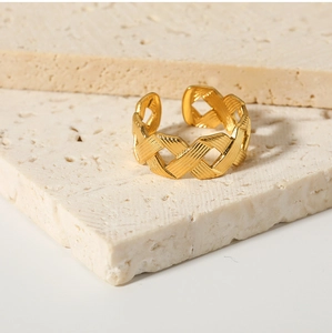 Detail of gold woven texture open ring displayed on a natural beige stone pedestal