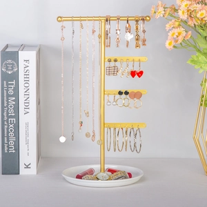 Detailed view of T-shaped golden metal jewelry stand with a white tray for earrings