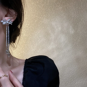 Detailed close-up of bow tassel earrings with sparkling zircon and silver needles