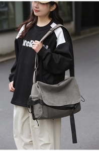 Detailed view of gray canvas messenger bag with adjustable strap worn by male model