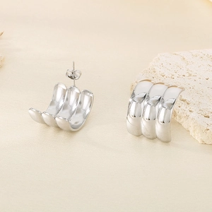 Macro shot of silver triple-row C-shaped wave stud earrings with mirror finish