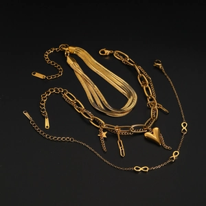 Close-up of a three-piece gold stainless steel jewelry set with layered snake chains and charms