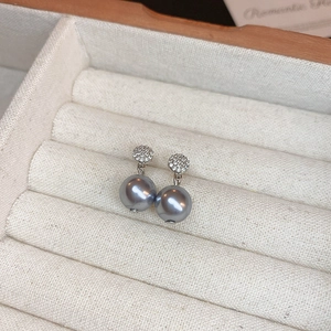 Détail de boucles d'oreilles perles grises avec clous en zircon sur boîte en velours