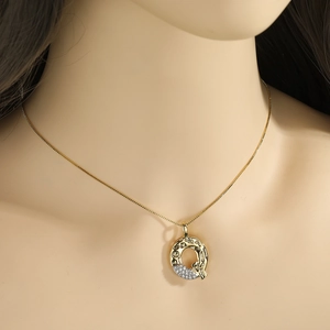 Detail view of gold Q letter necklace with sparkling cubic zirconia on the lower curve