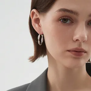 Minimalist S925 silver hoop earrings with twisted metal texture worn by a fashion model