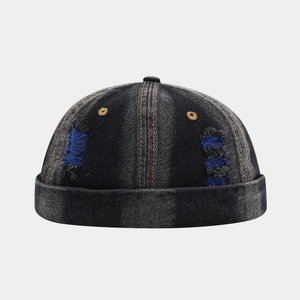 Detail of distressed dark blue denim docker hat with ripped holes and gold embroidery