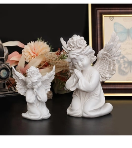 Close-up of white resin angel sculptures showing detailed wing textures and flower crowns