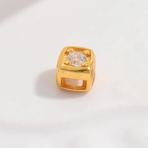Macro shot of 925 silver hollow cube bead with gold finish and a single sparkling zircon