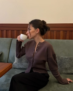 Detail of dark brown slim-fit knit cardigan with metal buttons in a cafe setting