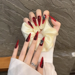 Extra long stiletto press-on nails in red marble design with 3D silver skull and bow charms
