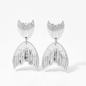 Détail des boucles d'oreilles queue de poisson argentées avec texture plissée radiale