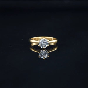 Classic gold titanium steel ring with moissanite in a four-prong setting and reflection