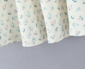 Gros plan du tissu floral avec petites fleurs roses et bleues sur une robe crème