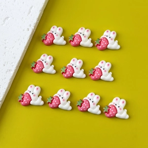 Flat lay of 10 cute resin strawberry rabbit charms for DIY crafts on yellow background